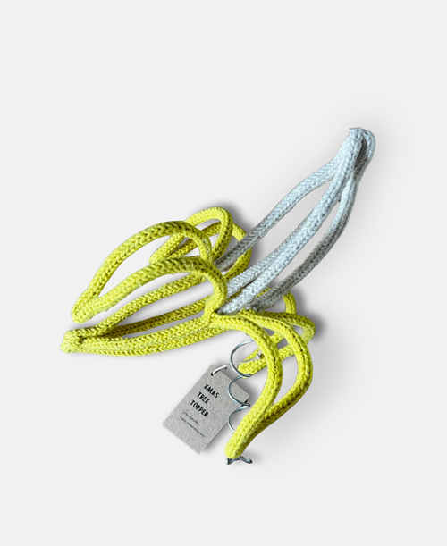 French knitted string and wire sculpted banana tree topper against a pale grey background
