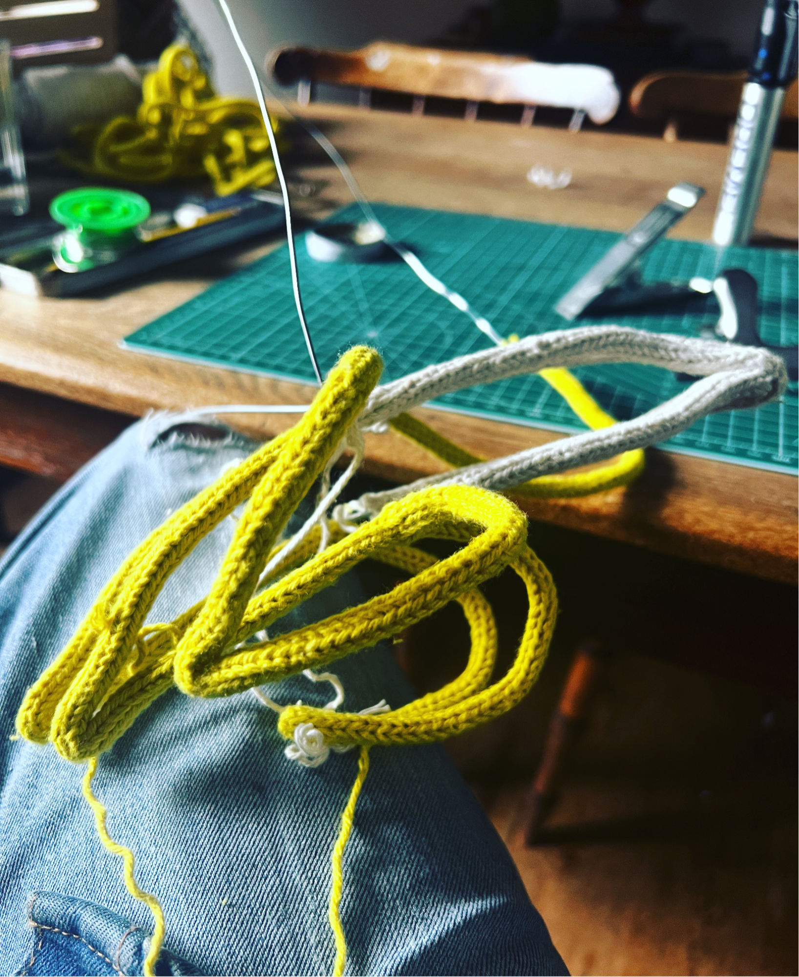 French knitted string and wire sculpted banana work in progress against a wooden table and green cutting mat