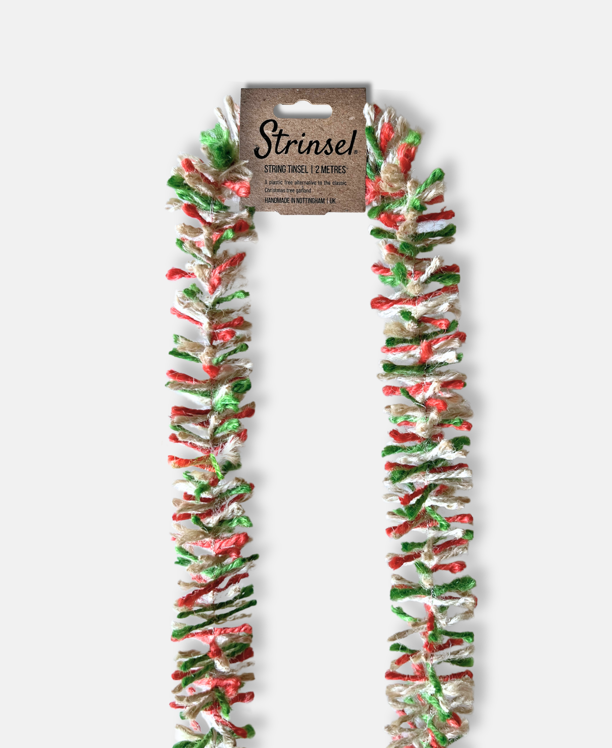 Red, white and green striped jute Strinsel string tinsel with a kraft label laid flat on a white background
