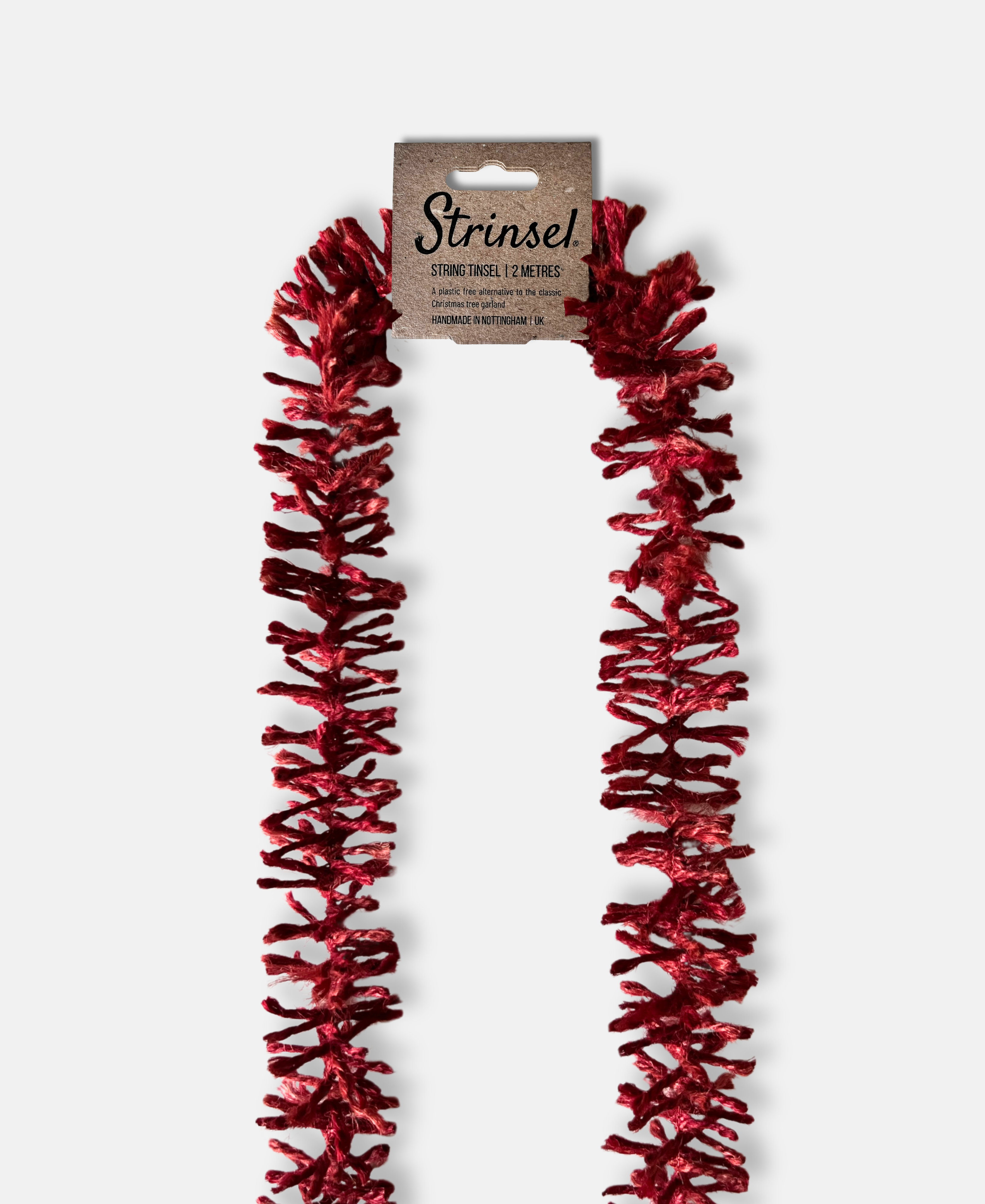 Deep Red Strinsel jute string tinsel with  a label on a pale grey background