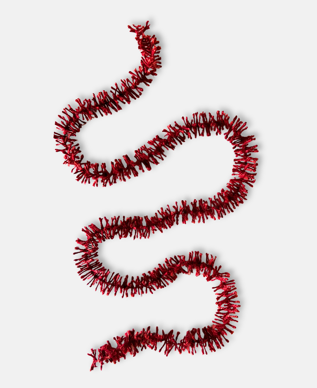 Deep Red Strinsel jute string tinsel on a pale grey background
