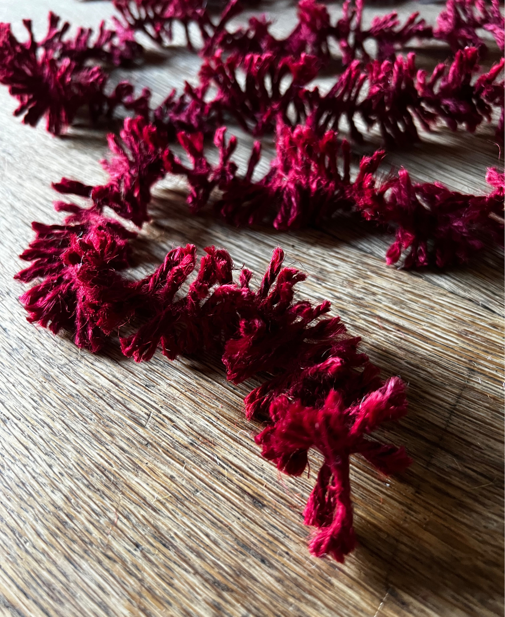 Deep Red Strinsel jute string tinsel on a wooden background