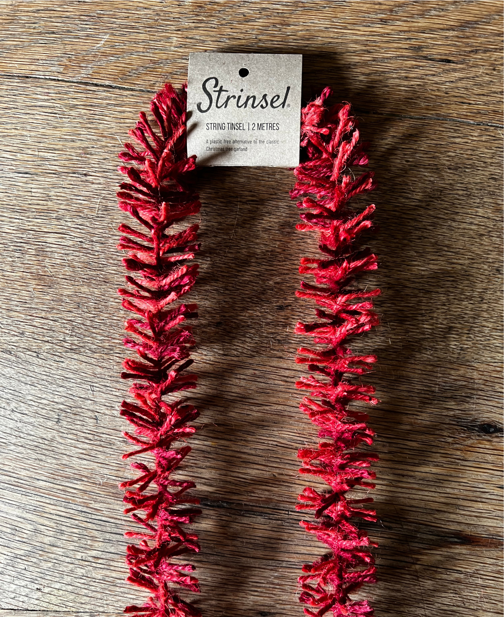 Deep Red Strinsel jute string tinsel with  a label wooden background