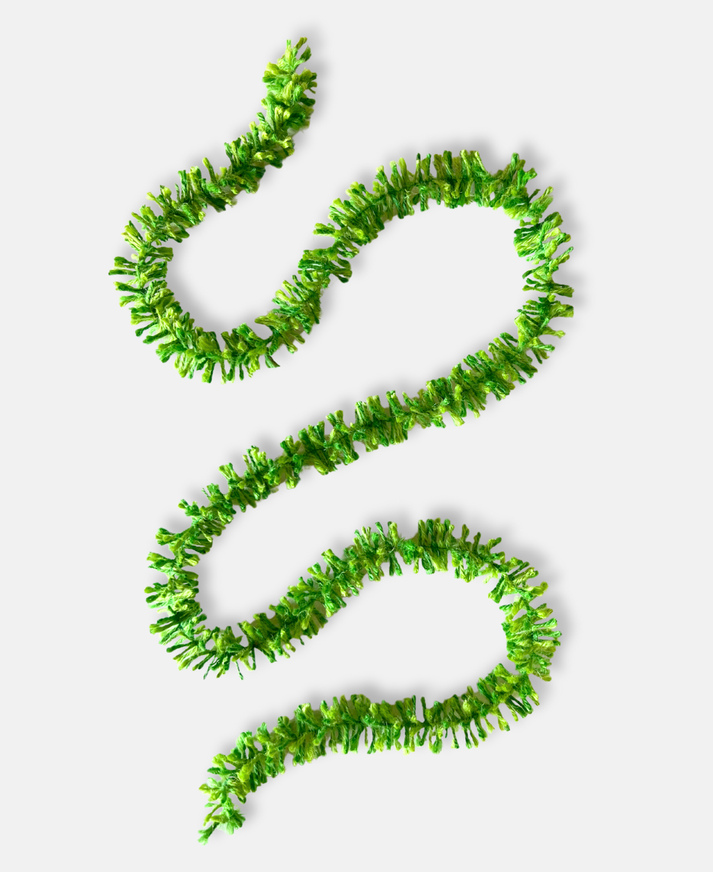 Green pop Strinsel jute string tinsel on a pale grey background