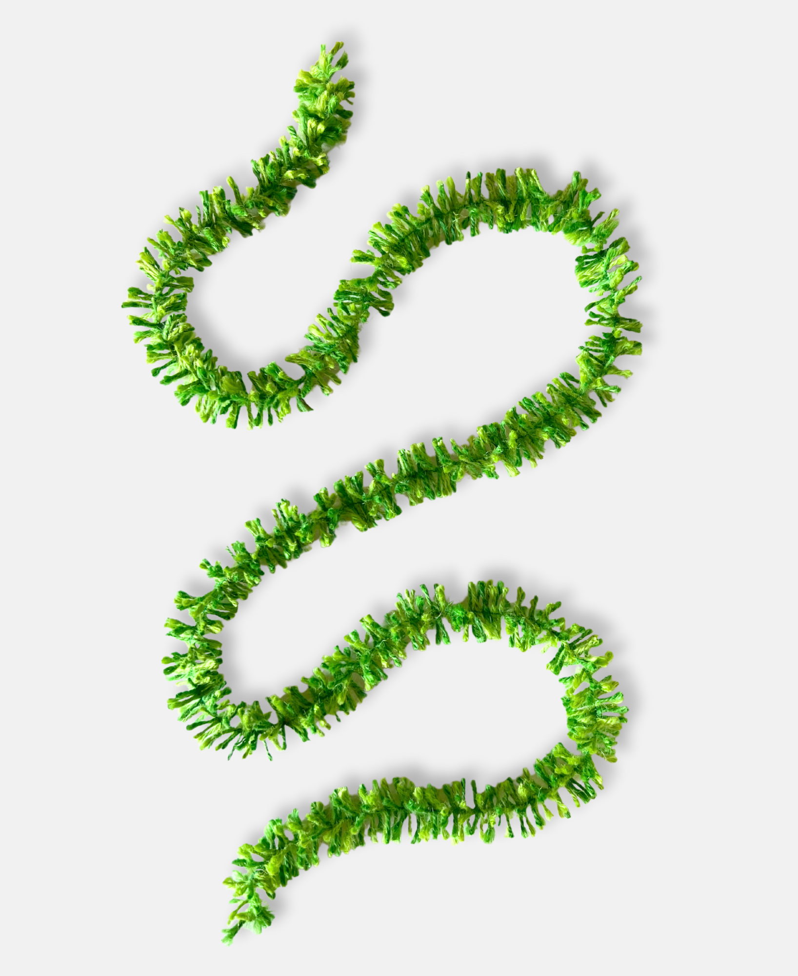 Green pop Strinsel jute string tinsel on a pale grey background