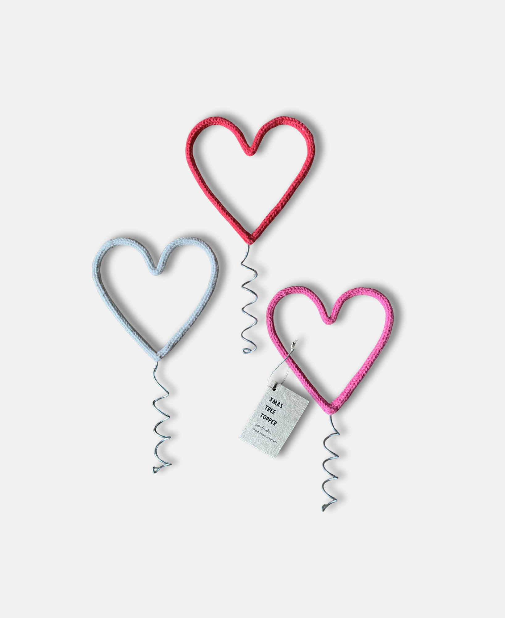 Three heart-shaped Christmas tree toppers on a white background