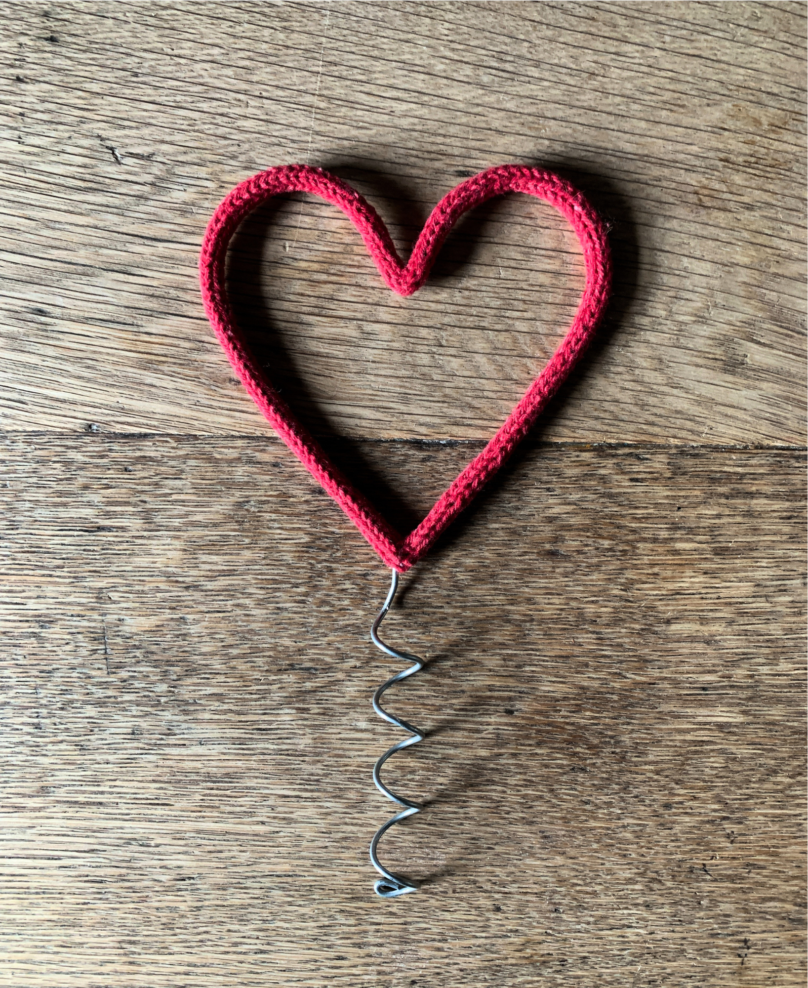 Red heart-shaped Christmas tree topper on a wooden surface