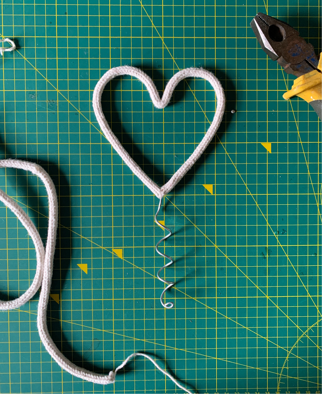 Heart-shaped wire Christmas tree topper on a green cutting mat with pliers.
