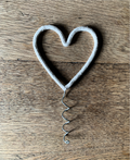 Heart-shaped string Christmas tree topper on a wooden surface