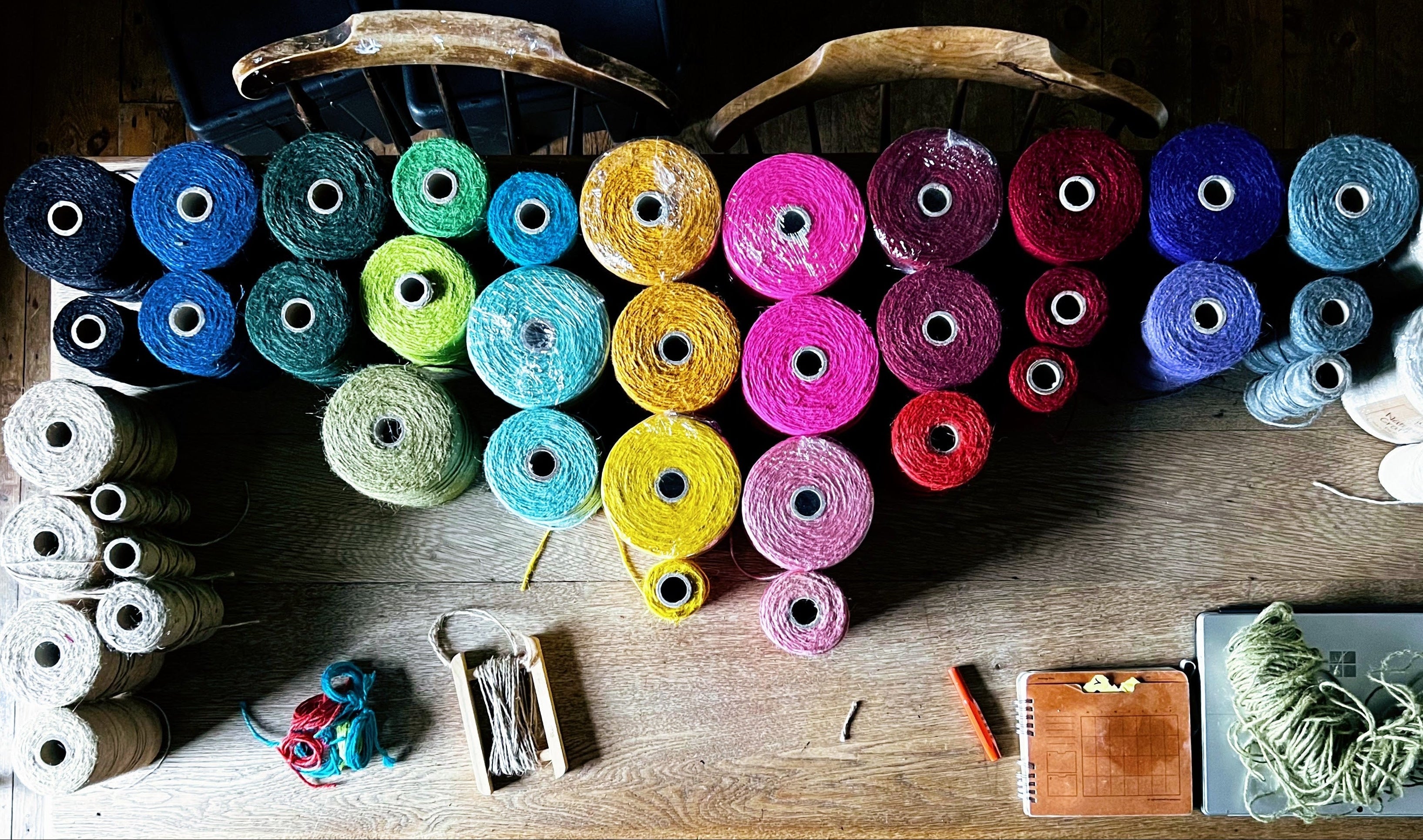 Colorful spools of string and twine arranged on a wooden surface with various small items.
