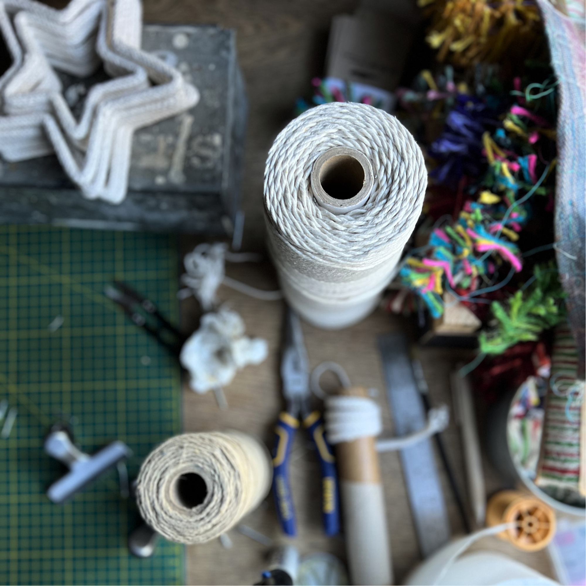 Spools of twine and craft supplies on  the table of This Thing is String founder Polly