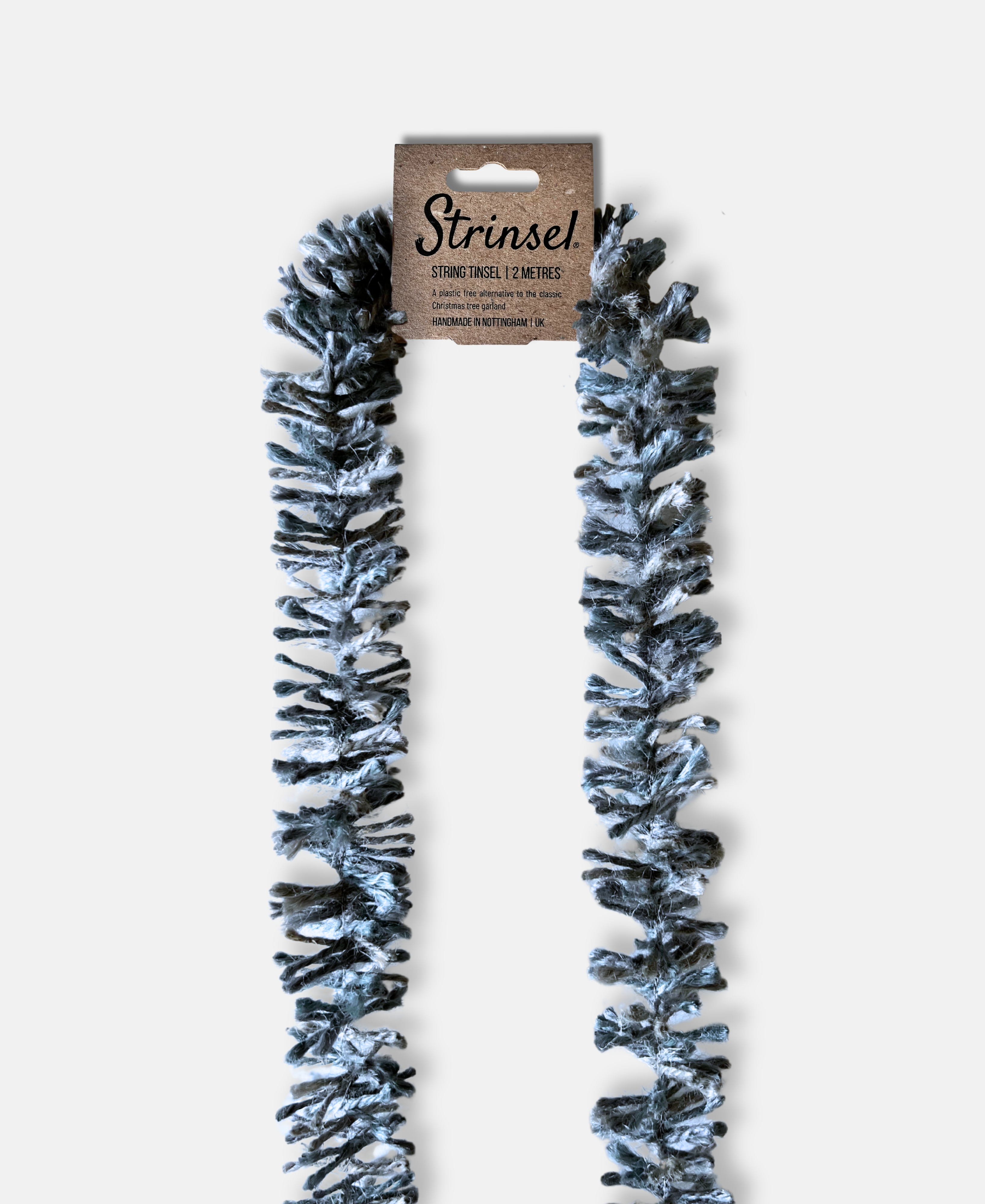 Silvery Pewter Strinsel jute string tinsel with packaging on a pale grey background
