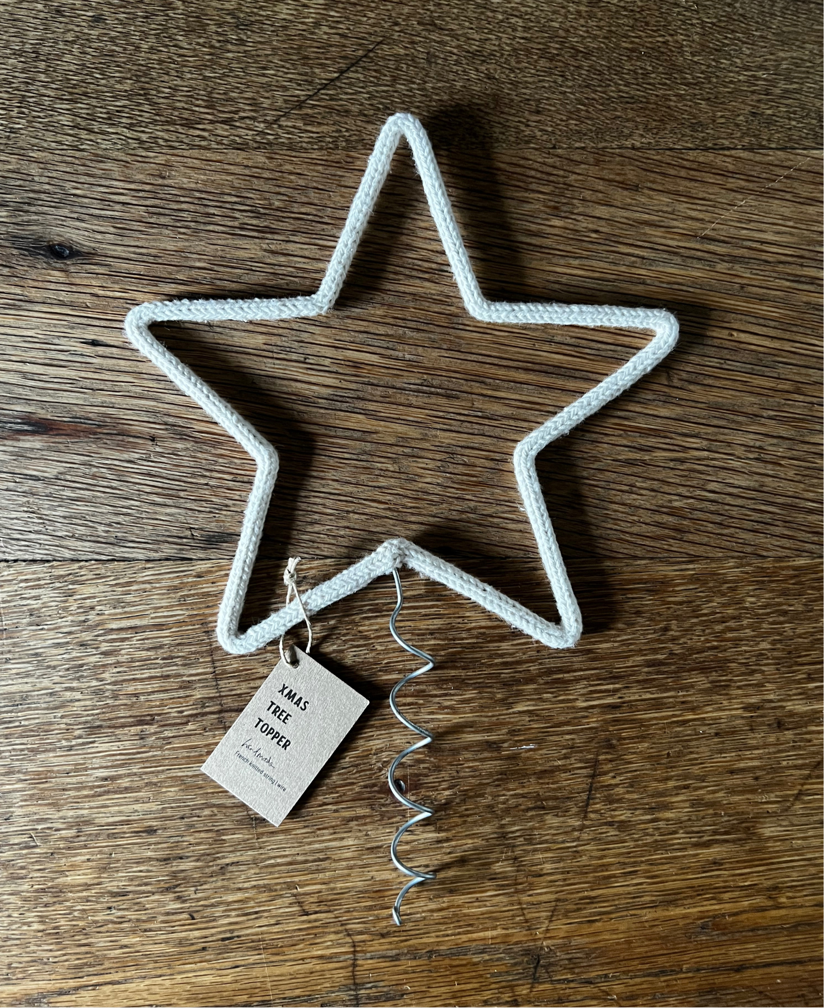 Star-shaped Christmas tree topper with a tag on a wooden surface