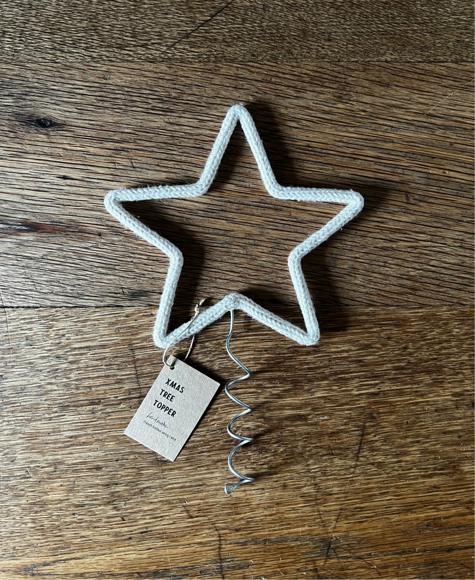Star-shaped Christmas tree topper with a tag on a wooden surface