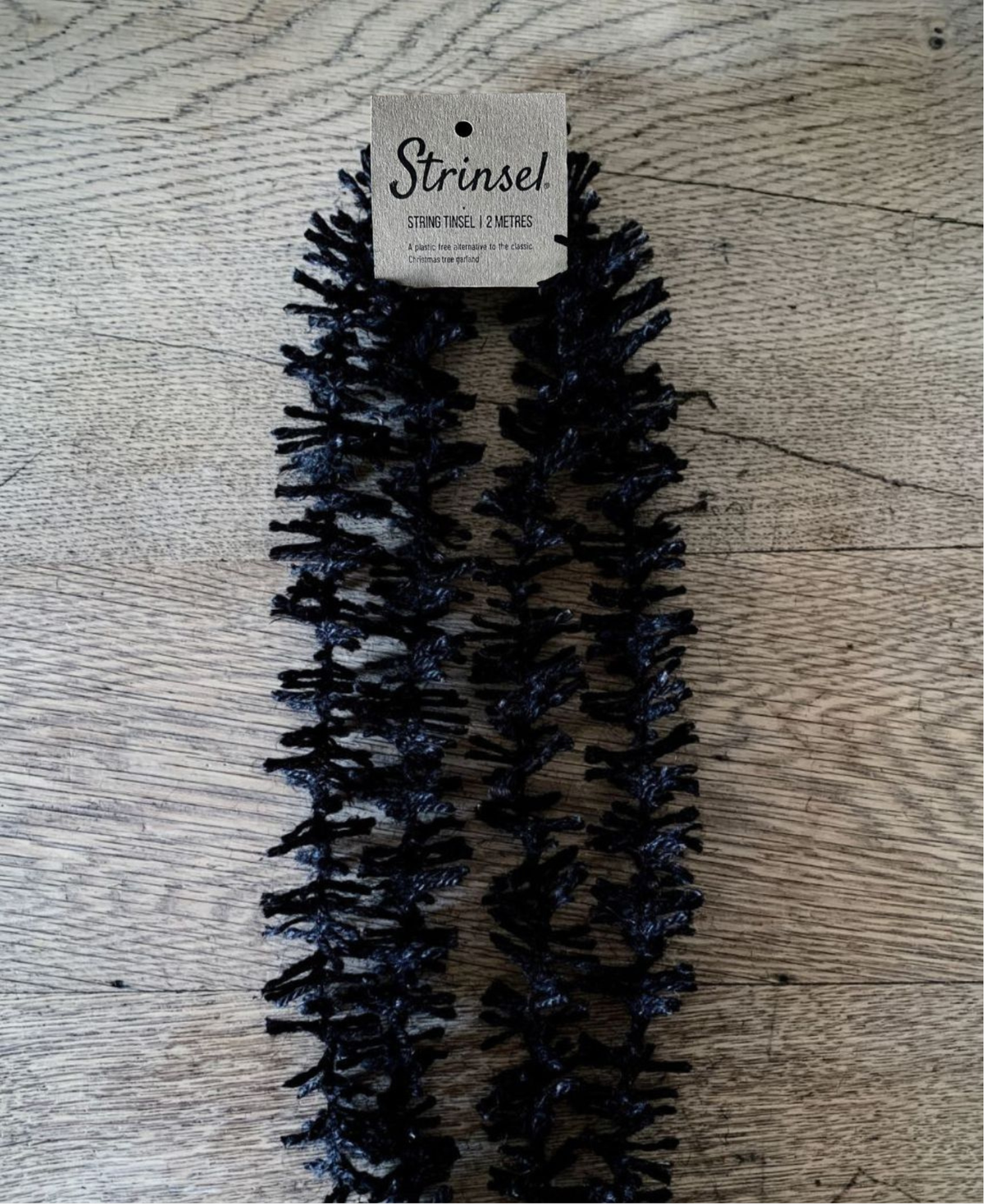 Black jute spider leg Strinsel string tinsel garland with kraft label laid out on an oak table top