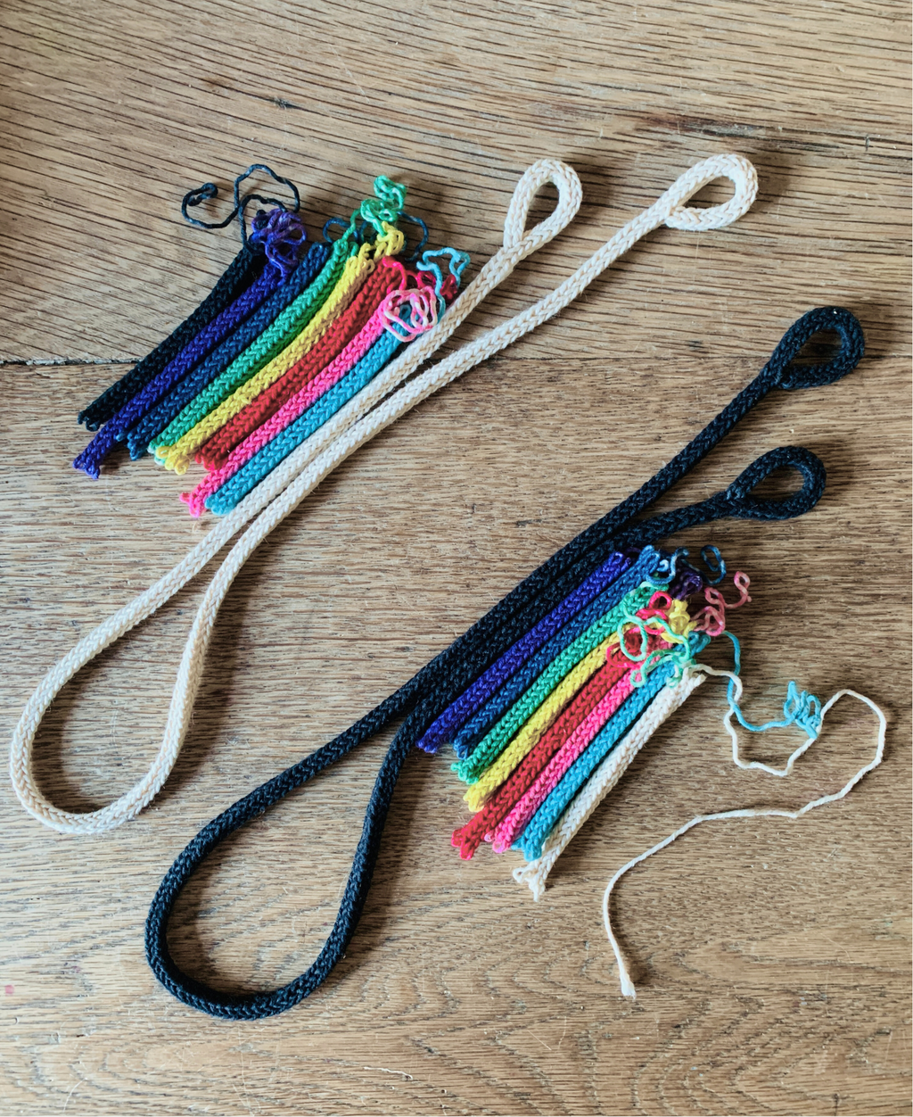 French knitted cotton string dyed in rainbow colours laid out on a wooden surface