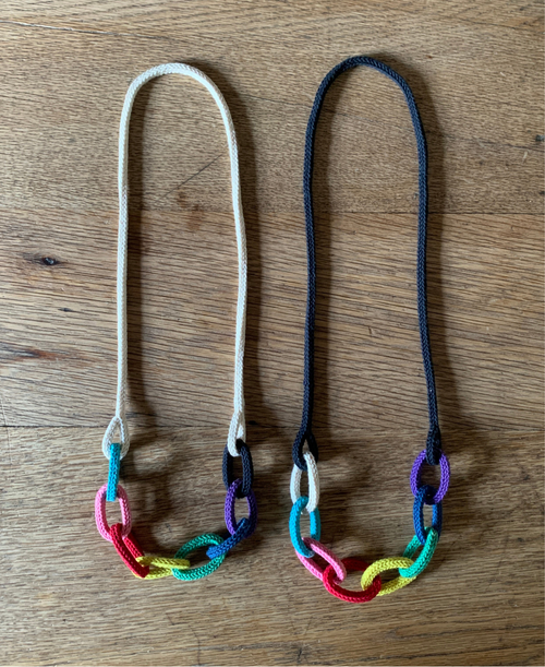 Two rainbow themed chunky chain "string bling" necklaces on a wooden background