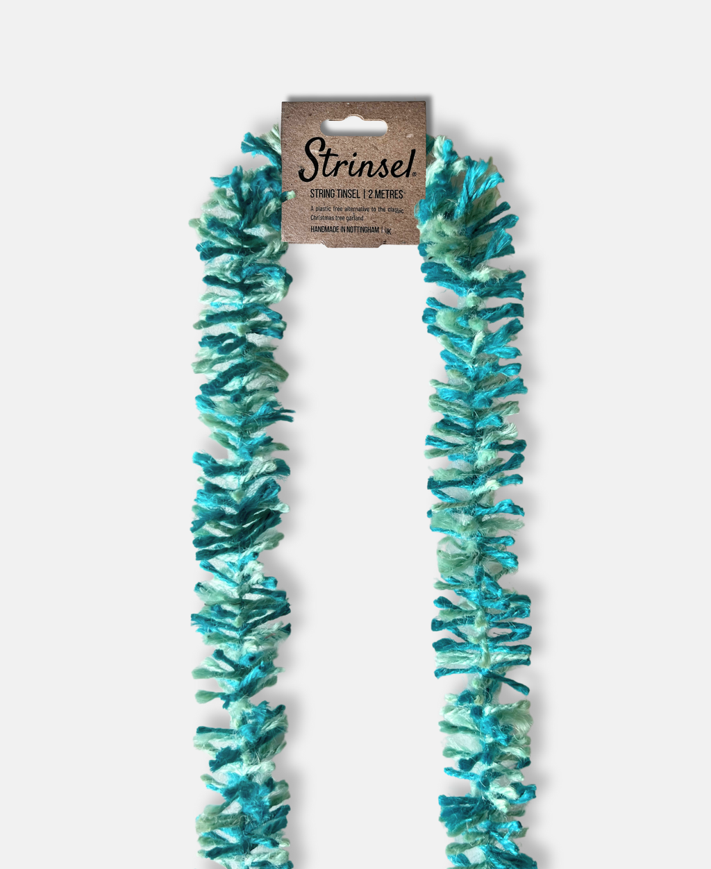 Teal and aqua Strinsel jute string tinsel with packaging on a pale grey background