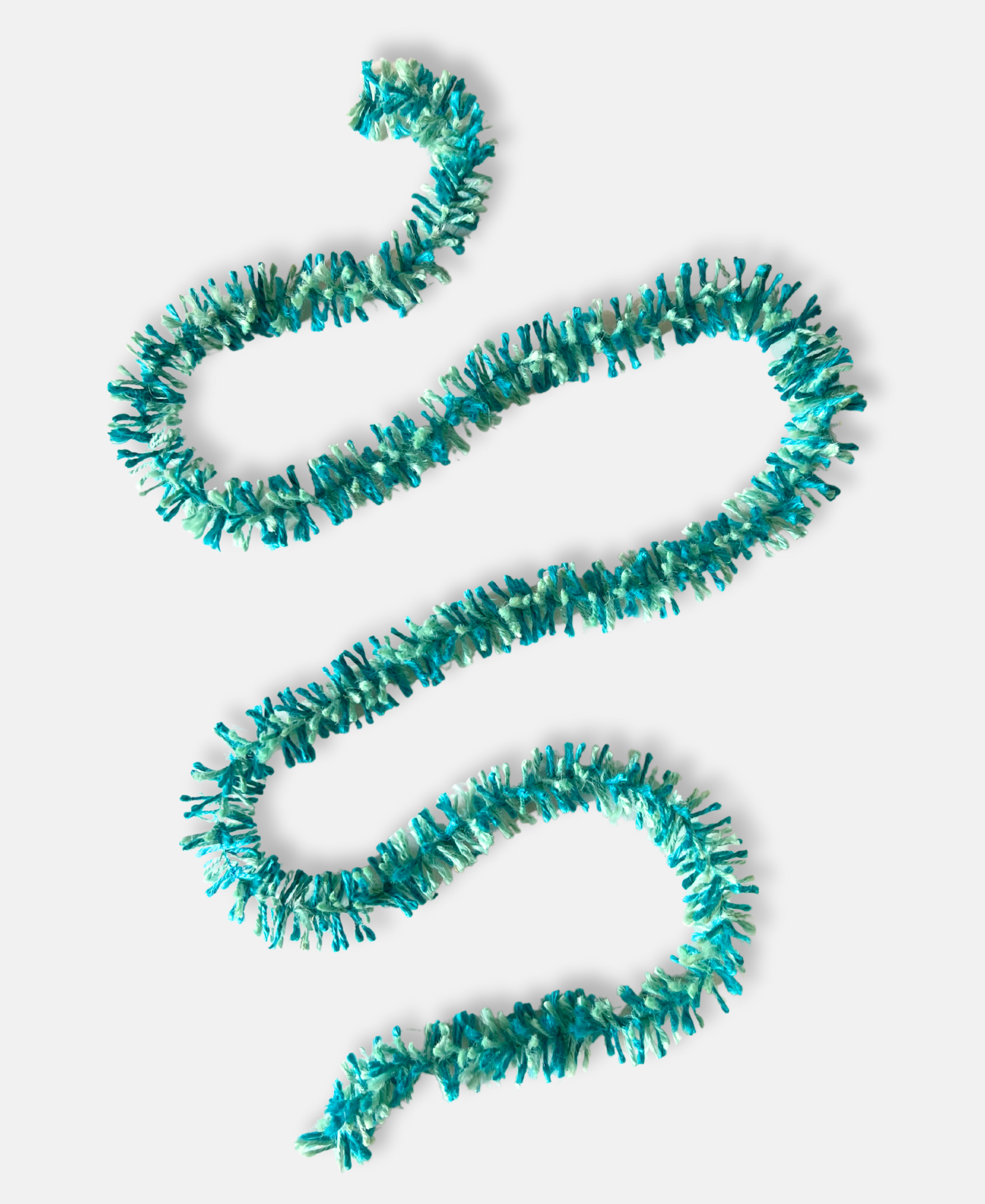 Teal and aqua Strinsel jute string tinsel on a pale grey background