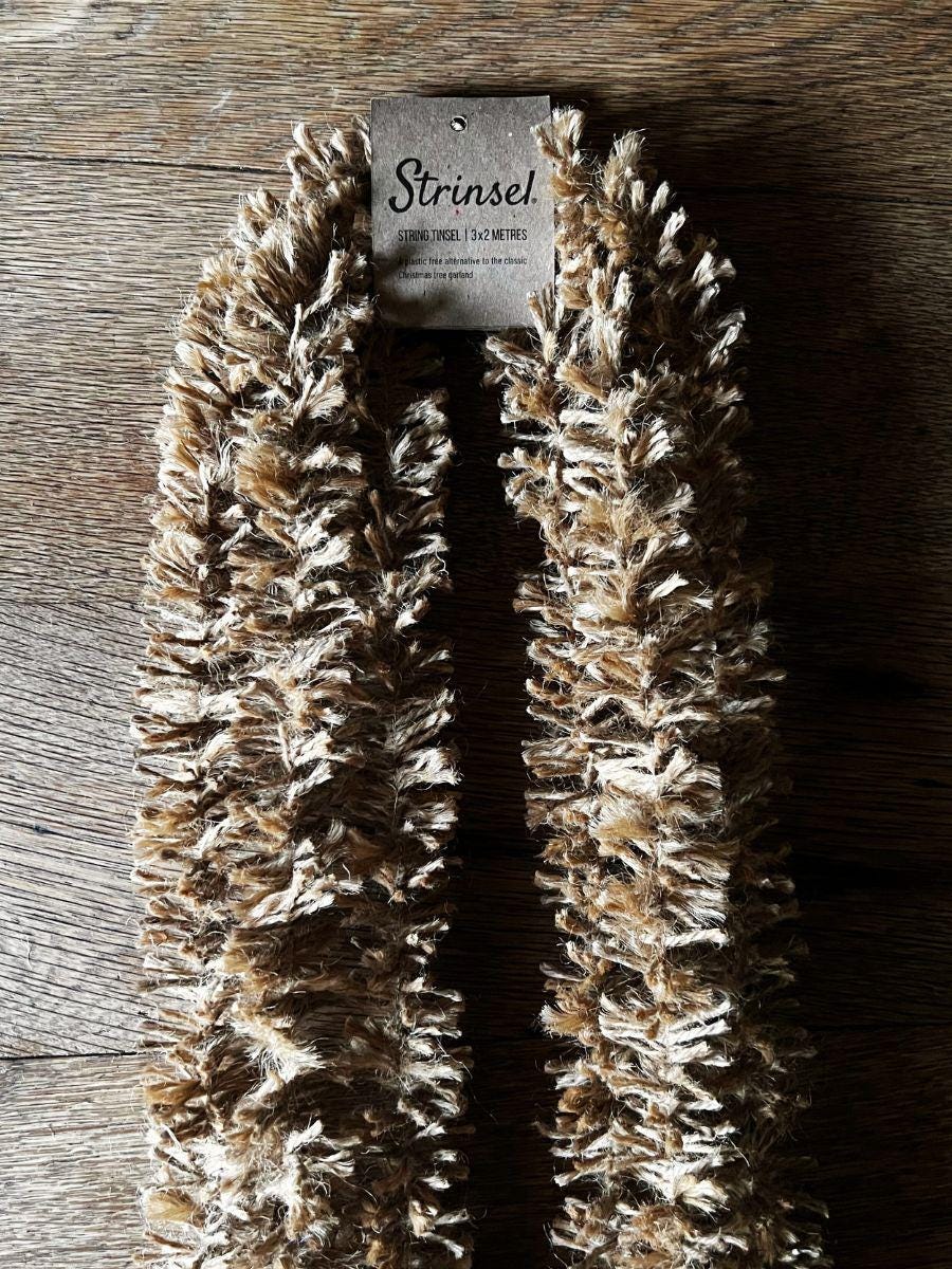 Naturally golden Strinsel jute string tinsel garland with packaging on a wooden background